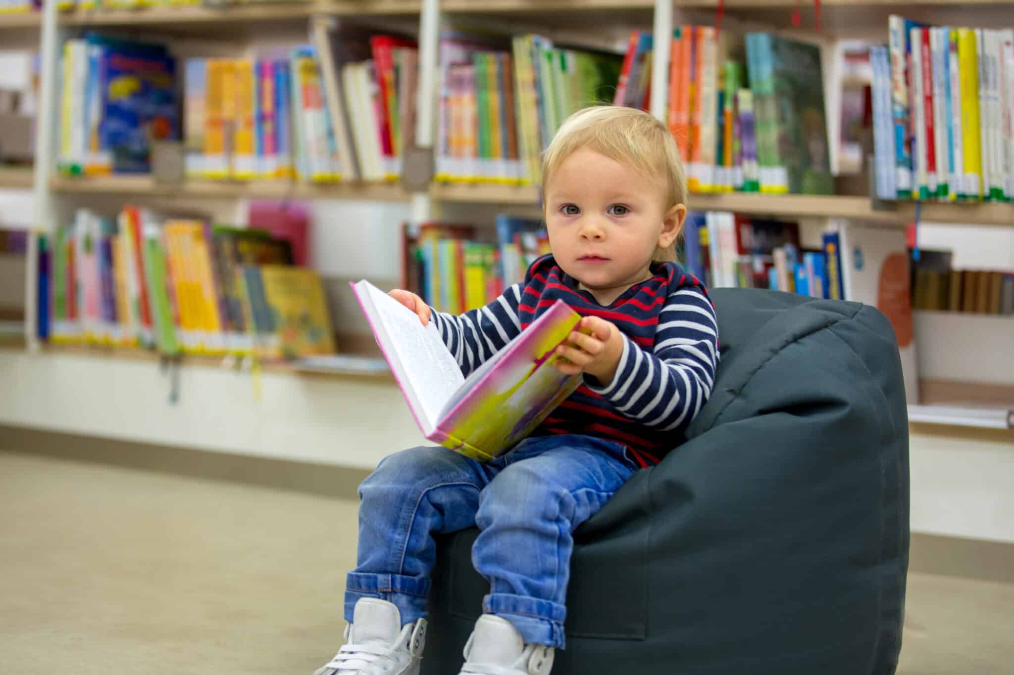 toddler boy on bean bag in bookstore looking at book